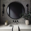 Bathroom with round black mirror, sink, and decorative elements.