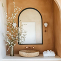 Bathroom interior with a stone sink, mirror, and decorative elements.