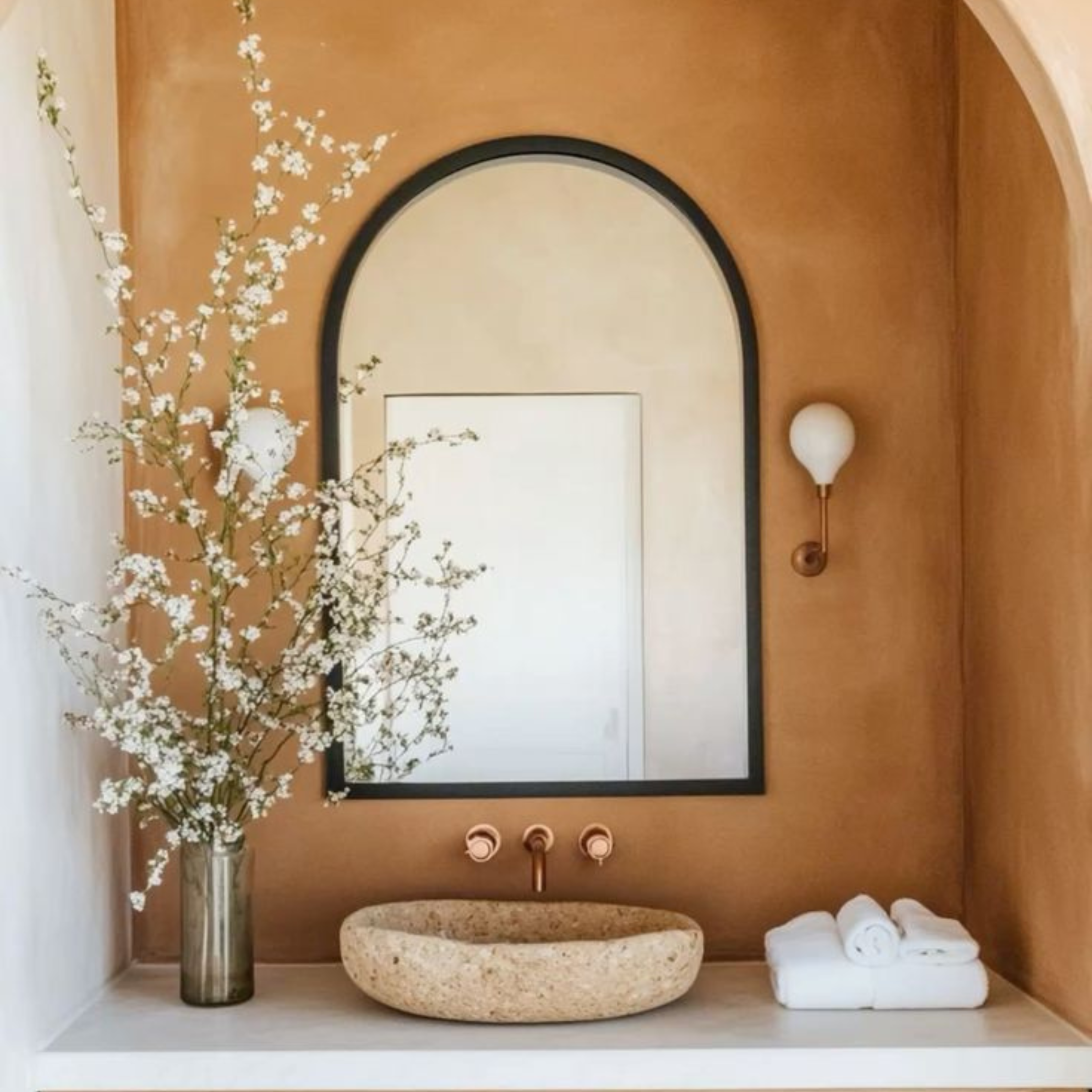 Bathroom interior with a stone sink, mirror, and decorative elements.