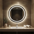 Bathroom vanity with a round illuminated mirror, sink, and decorative items.