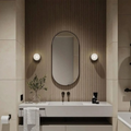 Modern bathroom vanity with oval mirror, light fixtures, and decorative elements.