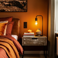 Cozy bedroom with warm lighting, bed, nightstand, and wall art.
